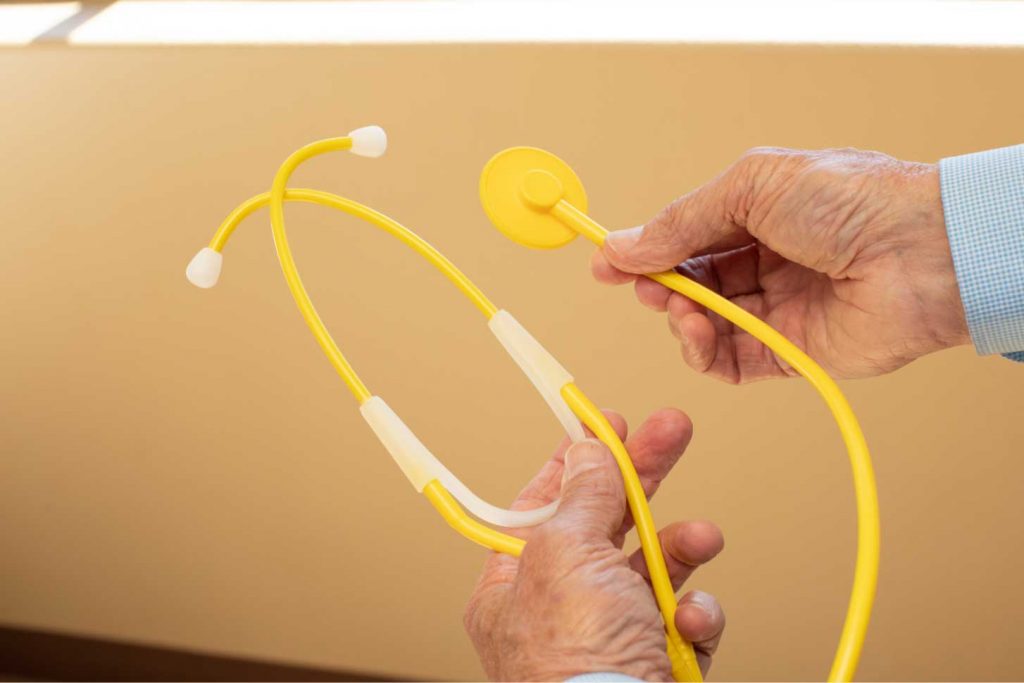 Disposable patient room stethoscope held by a physician